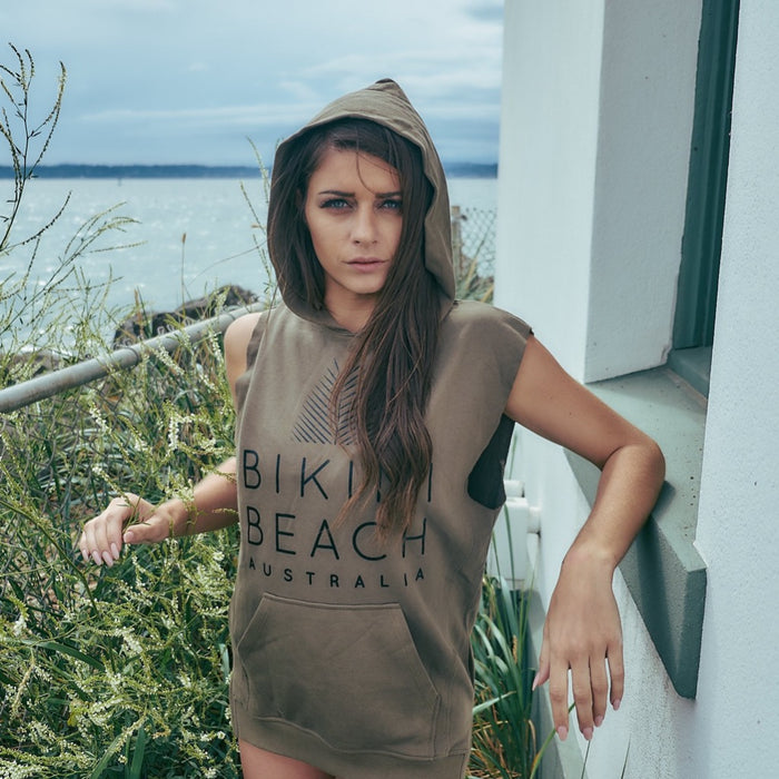 Model standing on a tarrus, having Surf Sleeveless Pullover Jumper in Olive, with writing text of Bikini Beach Australia