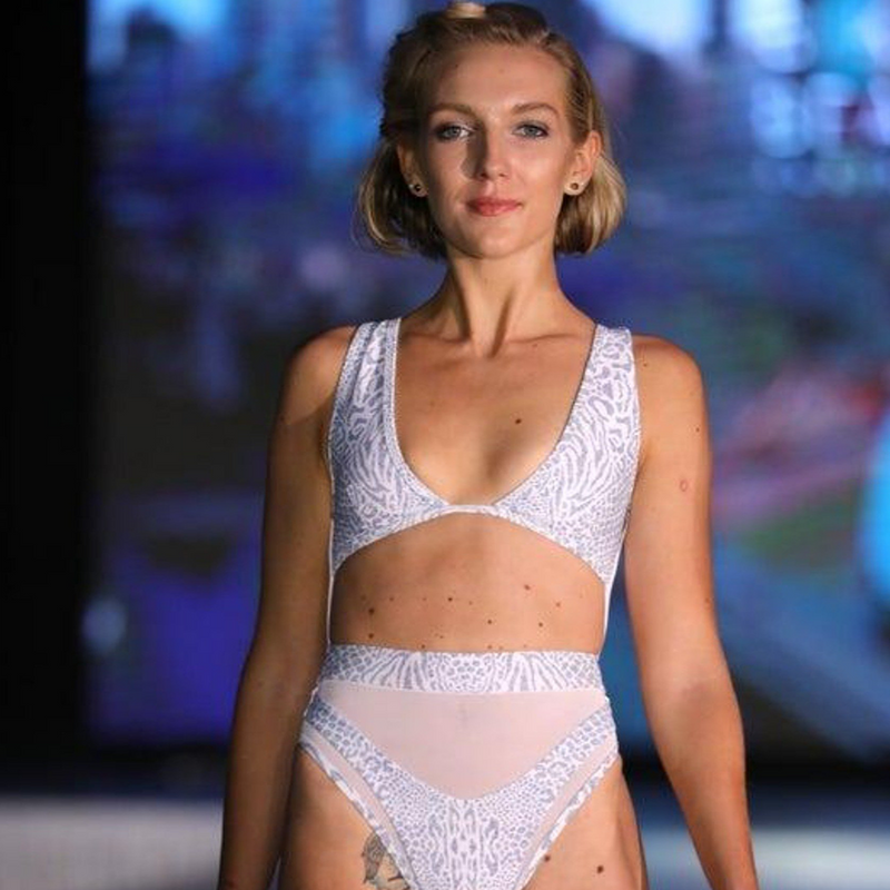 Model with light brown short hair on a ramp walk, ,having Hayman Island One Piece in Animale Glitterati Reversible, Plunging neckline, High waist cheeky cut bottom, Fully reversible zipper and mesh back detailing, BBA