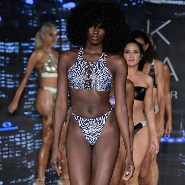 Model with strong curly hair, having Daydream Island Bikini Dark Animale Reversible, on a ramp walk along with other models